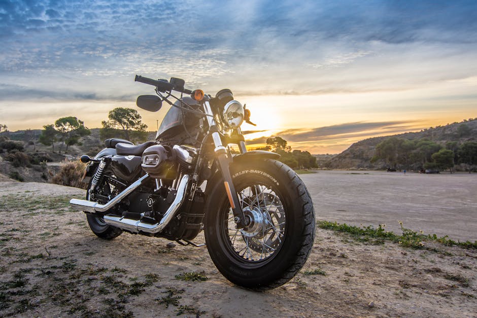 A Harley Davidson motorcycle parked outdoors against a stunning sunset sky, perfect for adventure and travel imagery.