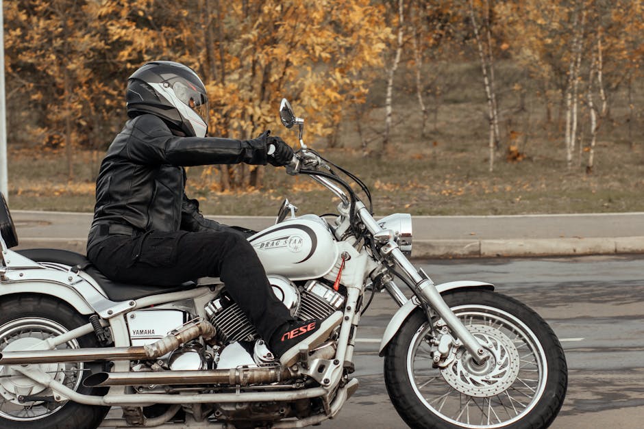 A motorcyclist in black leather riding a Yamaha Dragstar on a Moscow road in autumn.